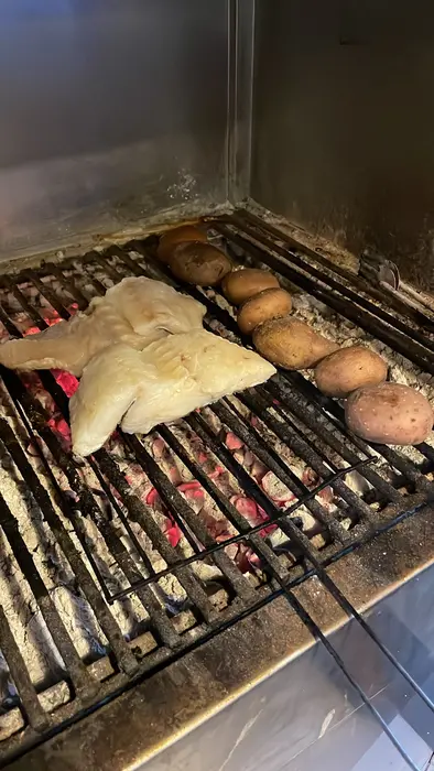 Bacalhau e batatas a assar na grelha sobre brasas de carvão